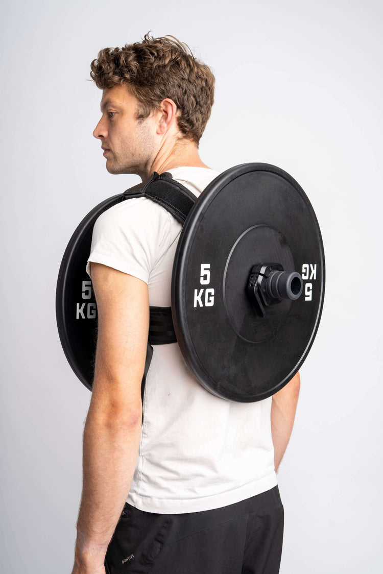 Mann mit einer verstellbaren Gewichtsweste bis 75 kg und Hantelscheiben auf dem Rücken.